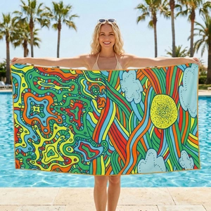 Microfiber beach towel with abstract sun and wave design by a blue swimming pool