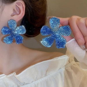 Detail of blue and white floral stud earrings featuring micro-pave crystals for women