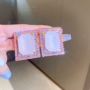 Macro shot of gold rectangle earrings with purple crystal center and pink diamond pavé