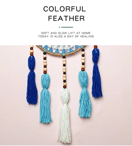 Detail of blue and white tassels with wooden beads on Evil Eye dreamcatcher wall decor