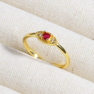 Macro view of a gold ring featuring a red gemstone set in a beige textured jewelry box