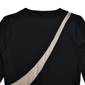 Détail d'une robe noire à manches longues avec une rayure beige diagonale élégante