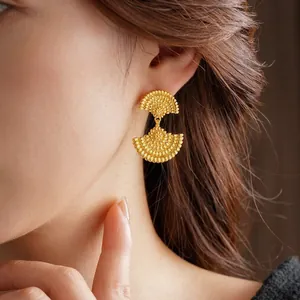 Vintage double fan gold plated earrings with textured finish worn by a model