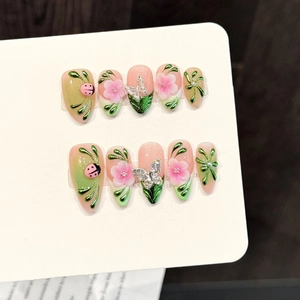 Dettaglio di unghie finte 3D con fiori, coccinella, tralci e sfumature rosa e verdi