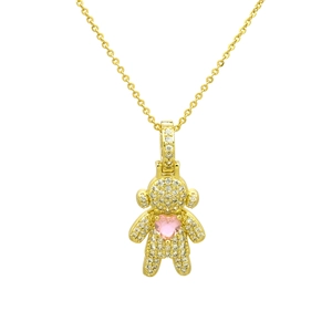 Macro detail of gold-plated bear pendant featuring white zircon and pink heart gemstone