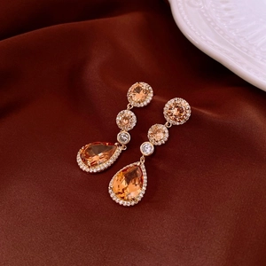 Macro detail of champagne droplet fringe earrings with pavé zircons on silk fabric