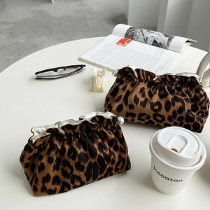 Leopard print cosmetic bags with pearl accents styled on a trendy white cafe table
