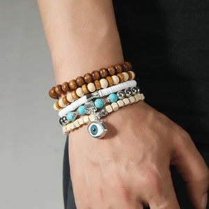 Close-up of handmade beaded bracelets with wood beads, Hamsa hand, and evil eye charm on wrist