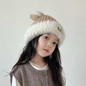 Close-up of khaki knitted children winter hat with fur trim and smile bear patch