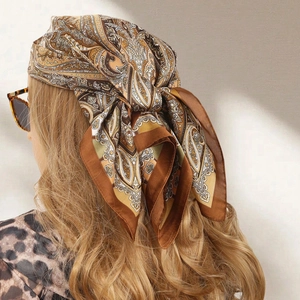 Elegant paisley print silk scarf in warm brown and khaki tones worn as a headband