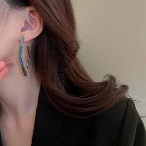 Close-up of geometric wave earrings with gradient blue rhinestones worn by a model