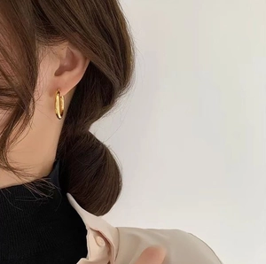 Close-up of a minimalist golden circular hoop earring worn on a model for a classic look