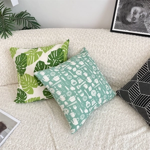 Detail of linen cushion covers with monstera leaf and geometric patterns on a white sofa