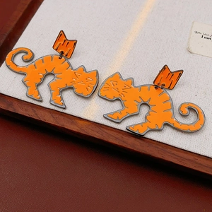 Detail view of orange cartoon cat stud earrings with grey stripes on a wooden tray