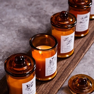 Amber glass scented candles on wooden tray featuring soy wax and botanical fragrances