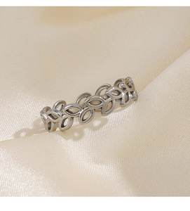 Detailed view of silver stainless steel leaf ring on a soft champagne silk fabric