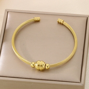 Detailed macro view of gold twisted wire cable bracelet with cylindrical bead ornament