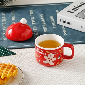 Detail of red Christmas ceramic mug set featuring gingerbread man and santa hat lid