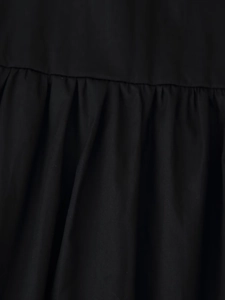 Detail view of black pleated fabric and stitching on a loose vacation style dress