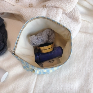 Detailed top view of blue and yellow checkered makeup bag with cotton texture and cosmetics