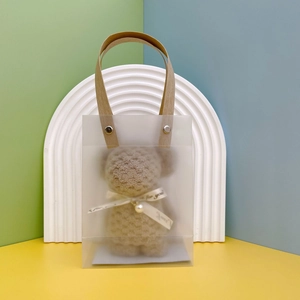 Frosted gift bag with brown handle showing a plush bear towel favor for guests