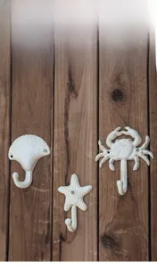 Detail der vintage Gusseisen-Wandhaken mit Muschel, Seestern und Krabbe auf Holz