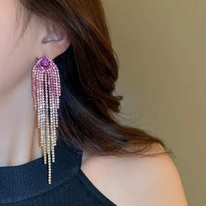 Close-up of elegant long tassel earrings with purple crystals on female model