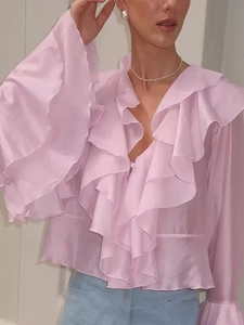Détail du chemisier rose à volants avec col en V et manches cloches en tissu satiné