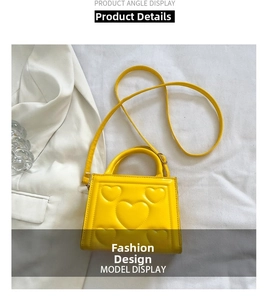 Détail d'un sac à main carré jaune vif avec motif de cœur en relief 3D et poignée assortie