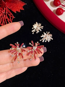 Macro shot of firework-shaped stud earrings with heart zirconia in red and gold finish