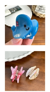 Detail of whale and floral acetate hair claws in blue, pink marble, and cream colors