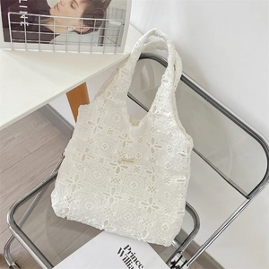 Détail du sac cabas en dentelle blanche brodée sur une chaise avec motifs ajourés