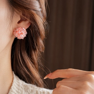 Close-up of model wearing pink cluster bead earrings with elegant knit sweater