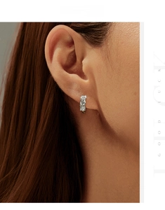 Macro shot of silver ear hoop with three vertical-set moissanite diamonds on the ear