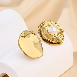 Elegant gold flower earrings with white pearls and luxury textured finish on a white stand