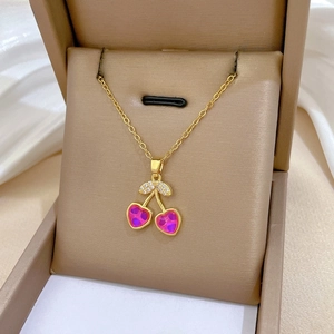 Macro shot of cherry pendant necklace with pink heart stones and zircon leaves