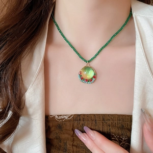 Detail of beaded green necklace with a vintage resin pendant on a model's collarbone