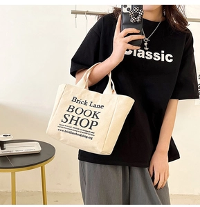 Detail of beige canvas tote bag with black Brick Lane Book Shop print held by model