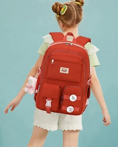 Rear view of high-capacity red school backpack with multiple pockets on a blue background