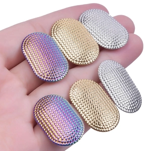 Close-up of small oval textured metal charms in rainbow, gold, and silver finishes