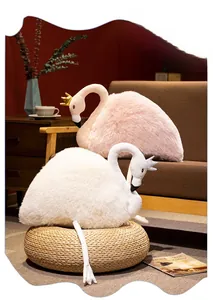 Detail view of plush swan dolls with crown accents on a cozy sofa setting