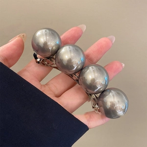 Minimalist hair clip with four grey metallic spheres on a silver spring base
