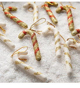 Macro detail of Christmas candy cane ornaments with glitter finish on snowy background