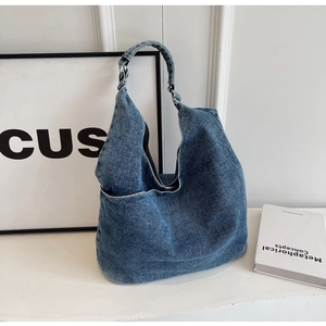 Minimalist blue denim hobo tote bag with wide shoulder strap and front pocket detail