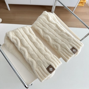 Minimalist cream cable knit wool warm socks with branded fabric label on a white tray