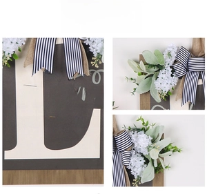 Detail of wooden welcome sign with letter background, striped bow and faux greenery