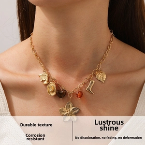 Detail of vintage gold necklace featuring flower, cowboy hat and boots charms