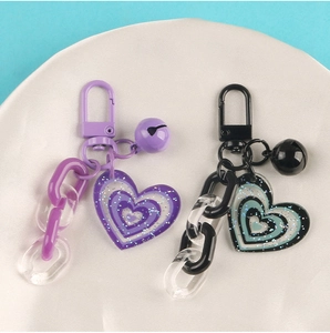 Close-up of purple and black glitter heart pendants with acrylic chains and bells
