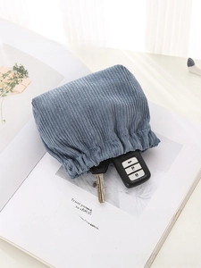 Detailed texture of blue corduroy storage pouch holding car keys on white magazine