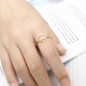 Detail shot of a minimalist gold mountain ring worn on the finger with a blurred backdrop